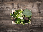 Fresh tasty green vegetables in wooden crates on a rustic wooden table