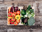 Fresh tasty colorful vegetables in wooden crates on a rustic wooden table