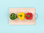 Fresh bell peppers on a wooden chopping board: healthy eating and food preparation