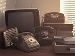 Vintage retro revival objects and second-hand appliances collection on a table: record player, television, radio and rotary dial telephones