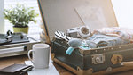 Traveler packing his luggage before leaving for a vacation: open vintage suitcase with clothes, camera and vintage record player, travel and retro revival concept