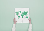 Woman completing a puzzle with a world map, she is putting the missing piece, globalization concept