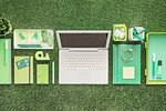 Laptop and green office accessories on lush grass, environment and technology concept