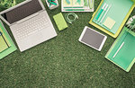 Laptop, digital tablet and office supply on lush grass, green business and technology concept