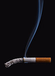 Cigarette burning on dark black background with smoke, stop smoking concept