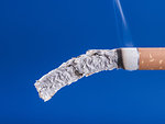 Cigarette burning on blue background, smoke addiction and quitting concept
