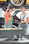 Experienced female auto mechanic checking tires before installing together with her colleague a new air suspension system in a modern automobile repair shop