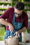 Ceramist Dressed in an Apron Sculpting Statue from Raw Clay in the Bright Ceramic Workshop.