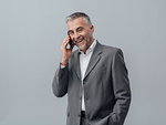 Confident smiling businessman having a phone call with his smartphone