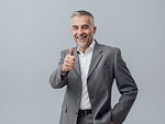 Cheerful confident businessman giving a thumbs up and smiling at camera