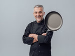 Confident smiling successful chef posing with arms crossed, he is holding a pan