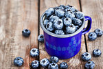 Fresh ripe blueberries and in blue enamel mug on rustic background
