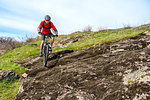 Cyclist in Red Jacket Riding the Mountain Bike Down Rocky Hill. Extreme Sport and Adventure Concept.