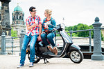 Tourists, woman and man, on scooter trip in Berlin taking a rest on the Museum Island