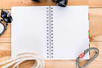 blank notebook on a spring with equipment for a complex trekking top view on a wooden background