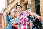 Young Couple, woman and man, on city trip in Berlin planning their Vespa tour using tablet PC