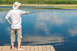 The fisherman on the pier with a fishing rod catches fish, the view from the back