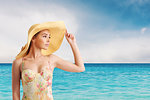 Girl with hat at the beach with a bright sea on background