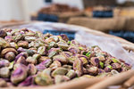 Background of basket of pistachios without shells, captured on street market, selective focus