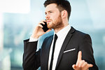 Young businessman at the office sitting at his desk and thinks about the work problem and busy talking on a phone