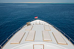 View over the bow of a large luxury motor yacht on tropical open ocean with sun loungers