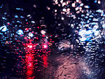 Blurred traffic lights bokeh with rain drops on glass a night