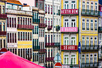 Close-up of colorful buildings with sign (Dress Well and Cheap Only Here) on an abandoned building in Porto, Norte, Portugal