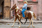 Cowboy on horseback riding in parade to the Parroquia de San Miguel Arcangel in St Michael Archangel Festival, San Miguel de Allende, Mexico