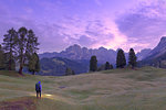 Hiker looks at pink light of dusk with Odle group in the background, Selva, Gardena Valley, South Tyrol, Dolomites, Italy, Europe