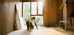 Construction worker measuring wood board in house