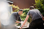 Construction workers using table saw to cut wood in driveway