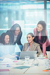 Smiling businesswomen using laptop in conference room meeting