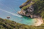 High-angle view down to one of the Porto Timoni beaches and a taxi boat approaching the bay, Afionas, Corfu, Greek Islands, Greece, Europe