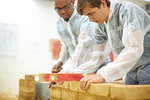 Male higher education students building brick wall in college workshop
