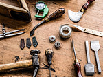 Leatherworker's workbench with hammer, tape measure and specialist tools, still life