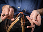Leatherworker stitching handbag in workshop, close up of hands