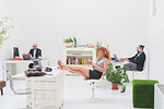 Businessmen working at office desks and businesswoman with her feet up