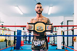 Portrait of male boxer with championship belt in boxing ring