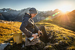 Hiker taking break with warm drink, Karwendel region, Hinterriss, Tirol, Austria