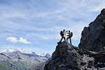 Hikers high fiving on peak of rock, Mont Cervin, Matterhorn, Valais, Switzerland