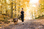 Woman jogging with dog in forest