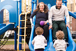 Boys looking at parents playing on slide