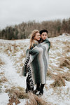 Couple wrapped in blanket in snowy landscape, Georgetown, Canada