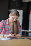 Portrait of a Smiling Woman Working on Tablet in her Workplace.