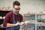 Portrait of Ceramist Dressed in an Apron Working on Clay Sculpture in the Bright Ceramic Workshop.
