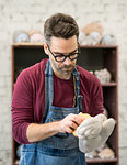 Portrait of Ceramist Dressed in an Apron Working on Clay Sculpture in the Bright Ceramic Workshop.