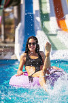 smiling pretty brunette lady in black bikini sitting on the inflatable ring in the swimming pool playing with water. Summer Vacation. Enjoying suntan. Weekend on resort