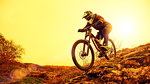 Professional Cyclist Riding the Mountain Bike Down the Rocky Hill. Extreme Sport and Enduro Biking Concept.