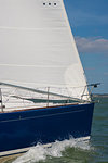 Close up of sailing boat, sail boat or yacht with a blue hull and white sails at sea