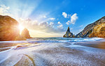 Portugal Ursa Beach at atlantic coast of Atlantic Ocean with rocks and sunset sun waves and foam at sand of coastline picturesque landscape panorama.